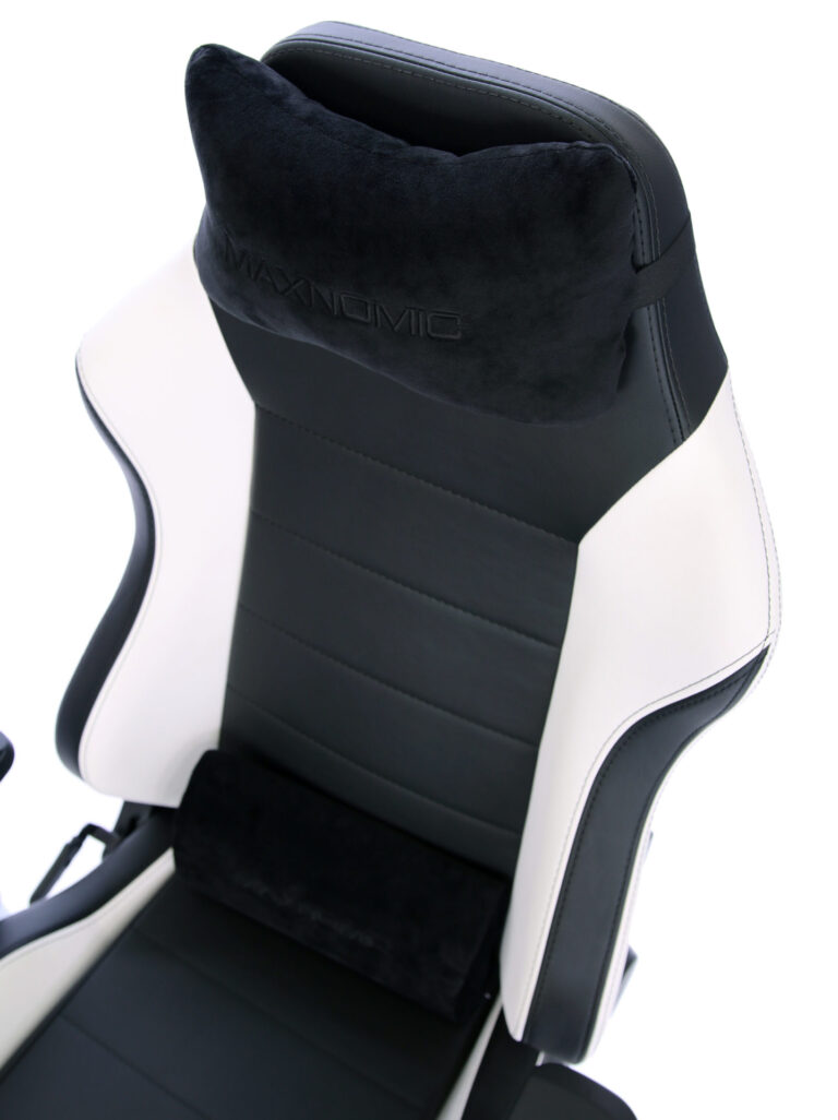 Close-up of the backrest of a black and white gaming chair with black head cushions.